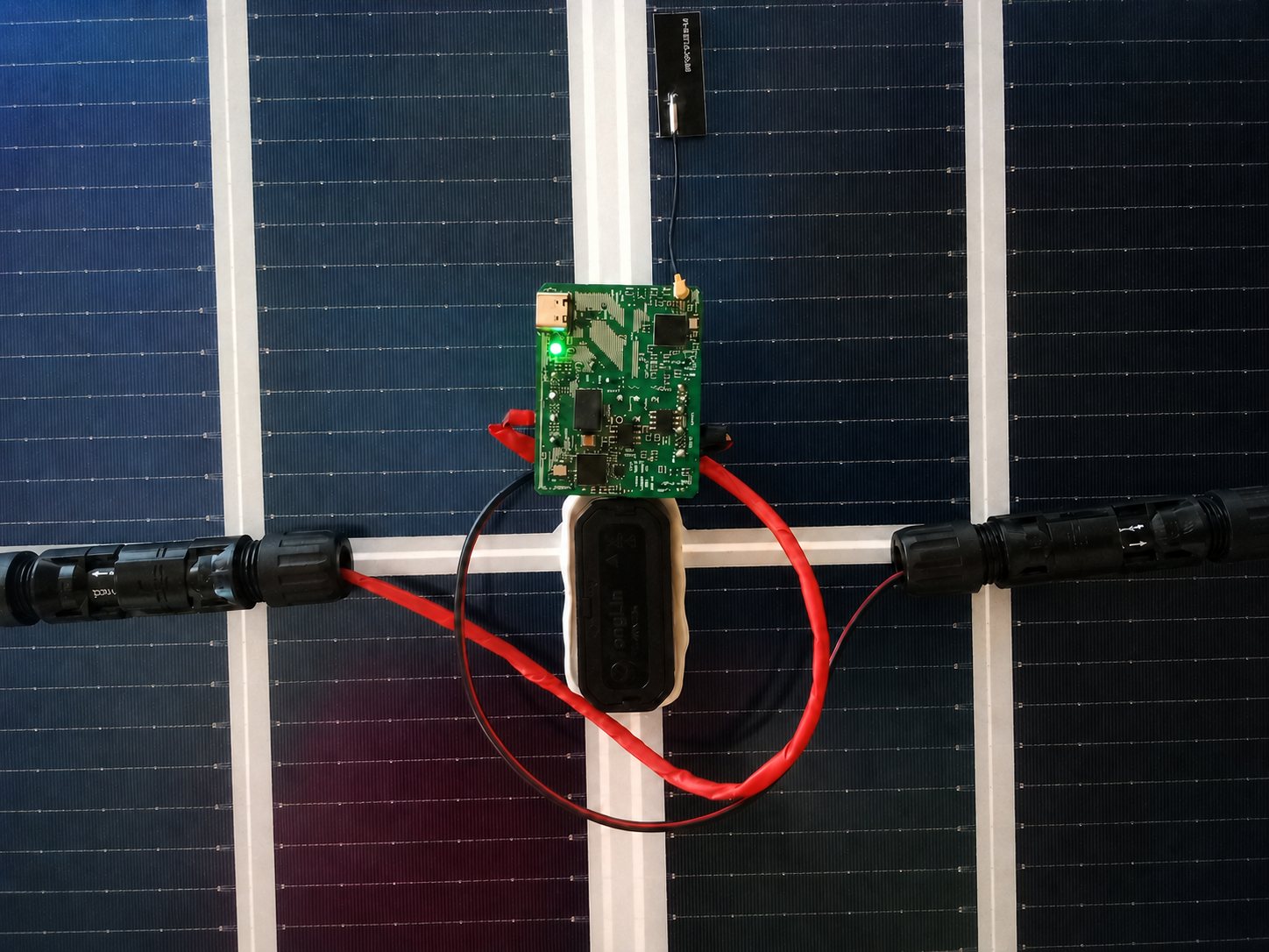 KLINO panel monitor mounted on the back of a solar module between the MC4 connectors